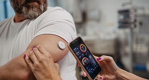 Patient checking glucose levels using a continuous glucose monitor on the arm